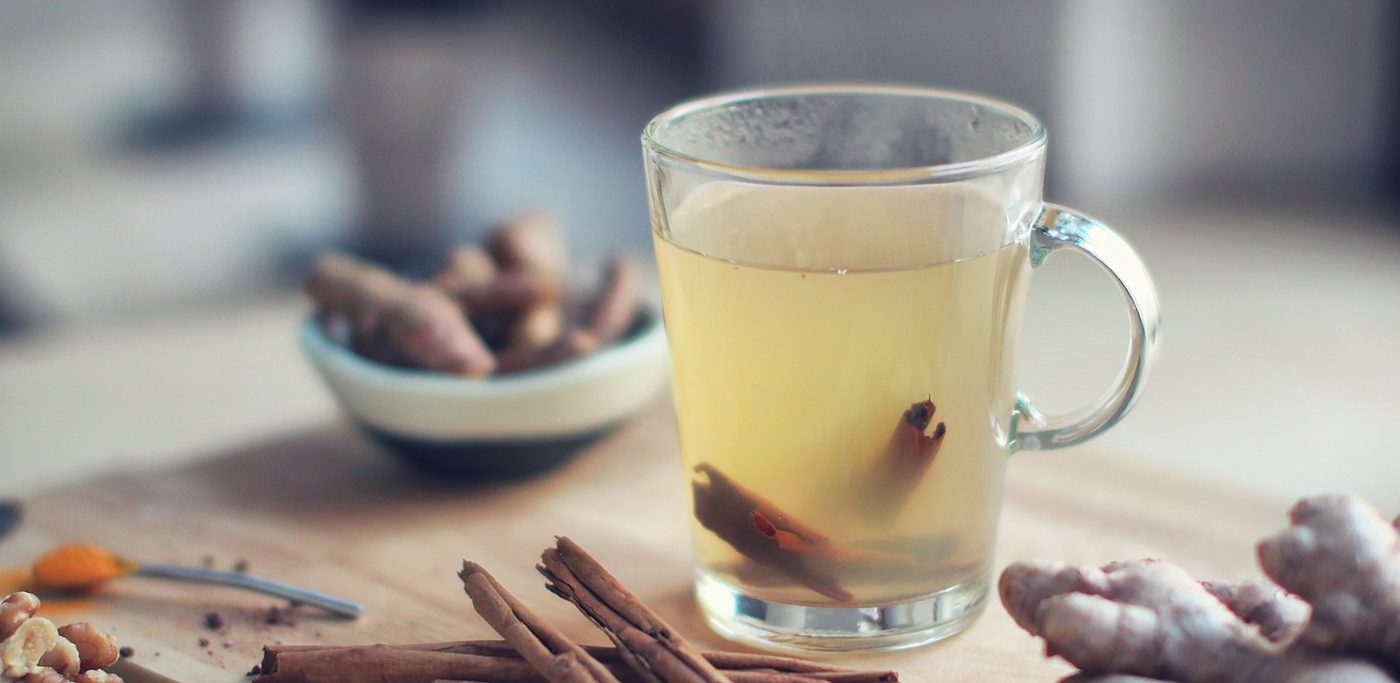 A warm cup of ginger and cinnamon tea with fresh ginger root and cinnamon sticks