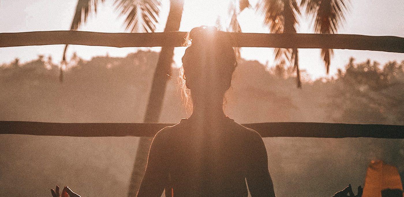 A woman meditating in the warm light of sunrise